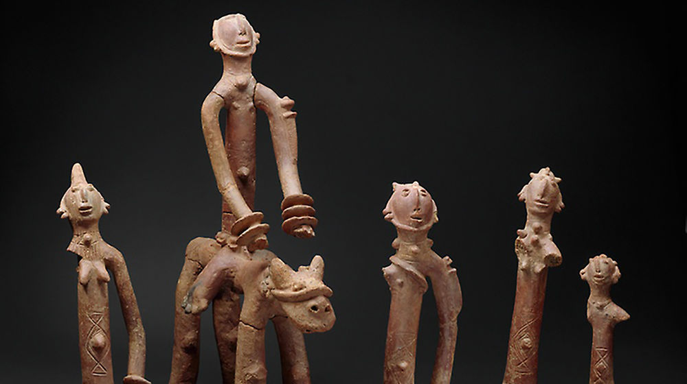 Five clay figurines, one of them on horseback, are seen against a black background.